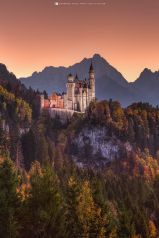 Bergpanorama in Bayern mit dem beleuchteten Königsschloss Neuschwanstein im Herbst zum Sonnenuntergang