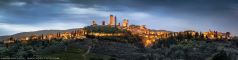 Landschaft in der Toskana mit der Stadt San Gimignano in Italien als weites Panorama zur blauen Stunde