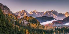 Alpenpanorama in bayerischen Allgäu mit den Königsschlössern Neuschwanstein und Hohenschwangau im Herbst mit Morgennebel zum Sonnenaufgang