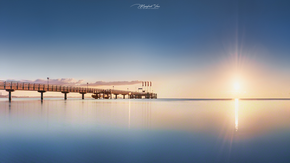 Seebrücke von Scharbeutz an der Ostsee bei ruhiger See zum Sonnenaufgang